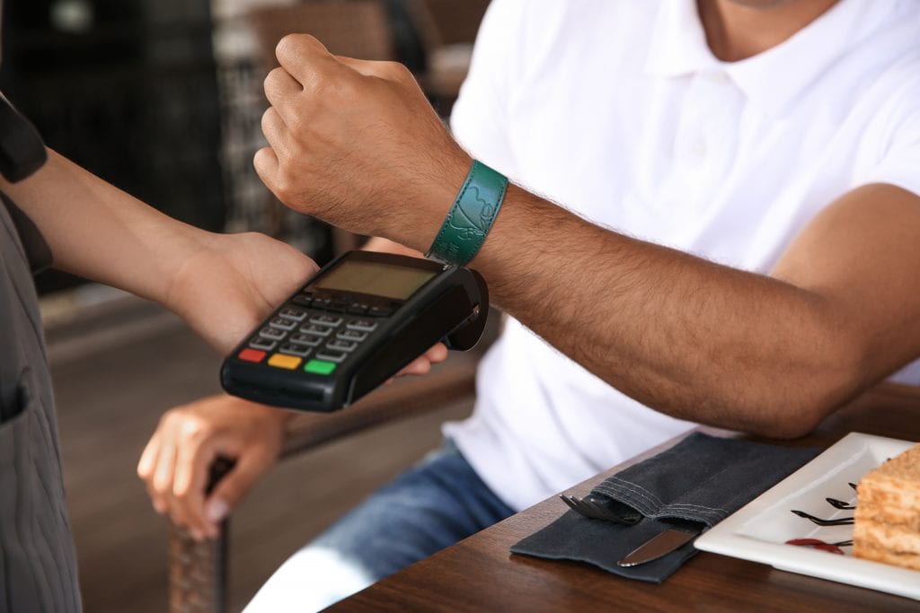 Man making payment with smart watch in cafe, closeup